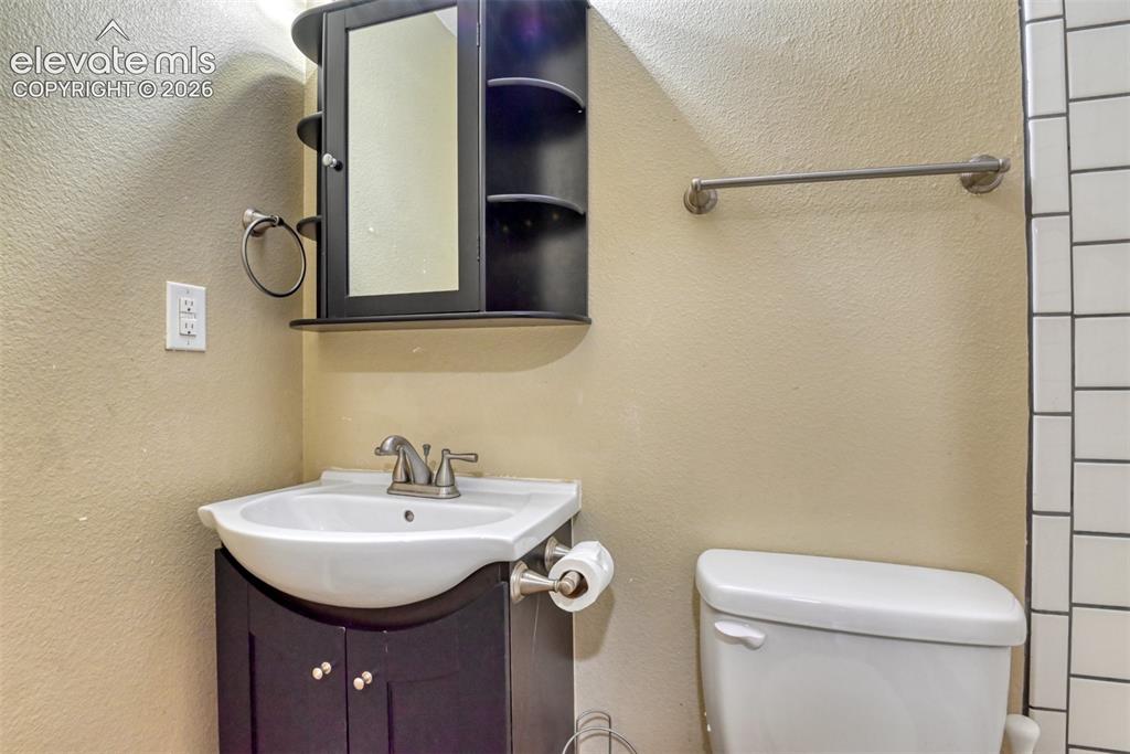 Image 30 of 35: Bathroom featuring a dark wood-finish vanity with an integrated sink, brush