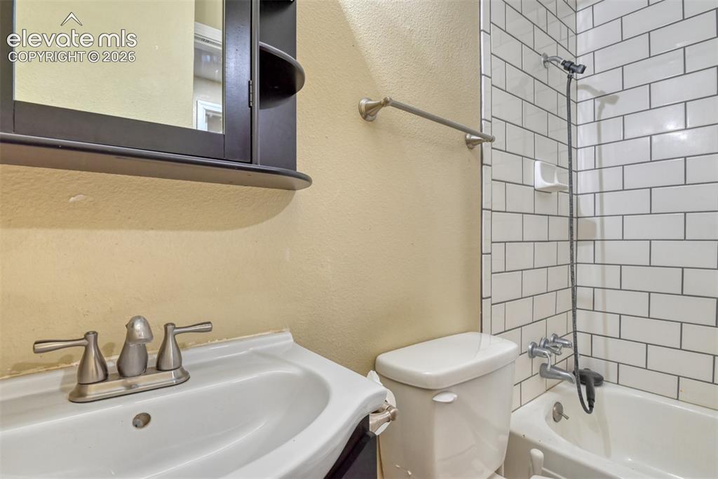 Image 31 of 35: Bathroom featuring a white ceramic sink, a dark wood-finish medicine cabine