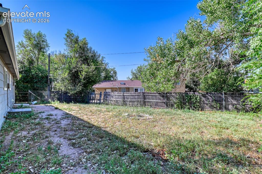Image 35 of 35: Expansive rear yard featuring a wooden privacy fence, mature trees, and a c