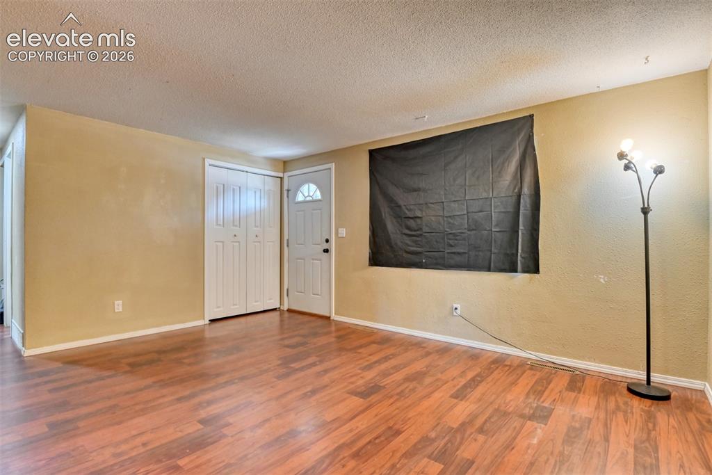 Image 6 of 35: Spacious interior with wood-finish flooring, light-toned wall paint, and wh