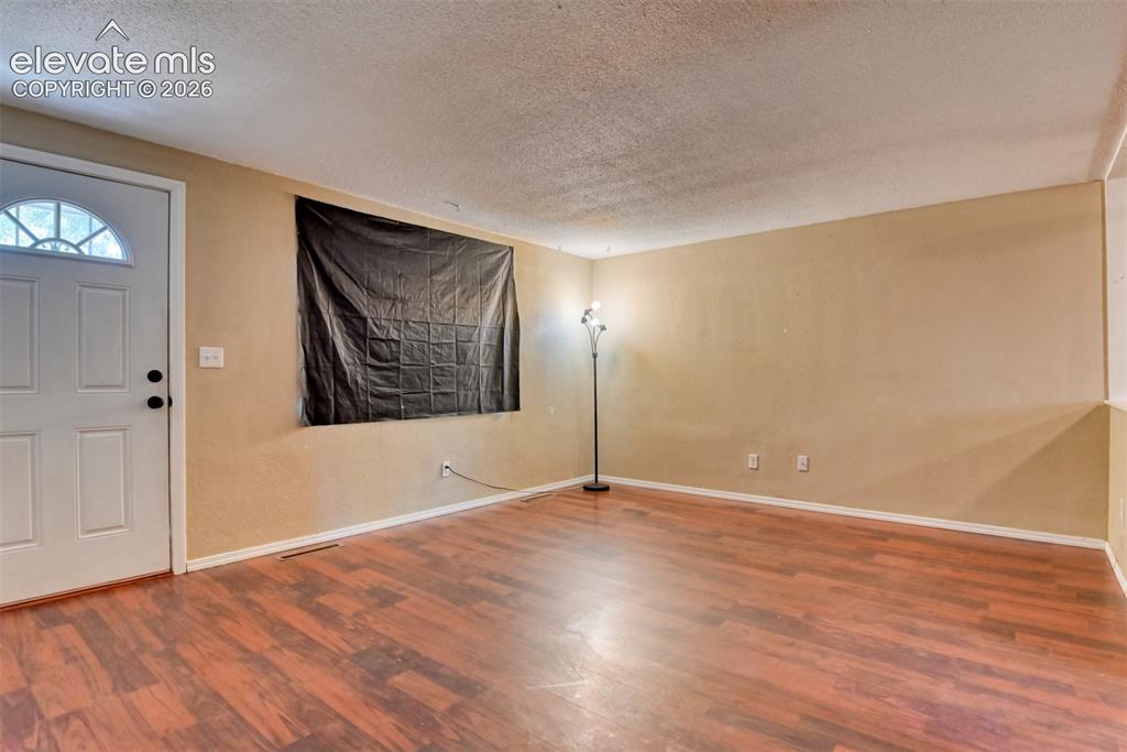 Image 7 of 35: Spacious interior room featuring wood-finish flooring, neutral wall tones, 