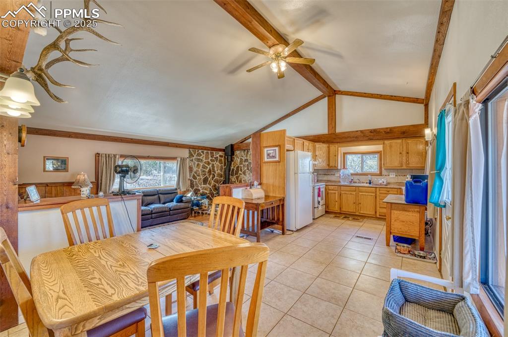 Image 10 of 45: Dining area with a wood stove, ceiling fan, and light tile patterned floors