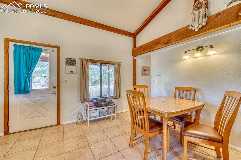Image 12 of 45: Dining area featuring light tile patterned floors, baseboards, beamed ceili