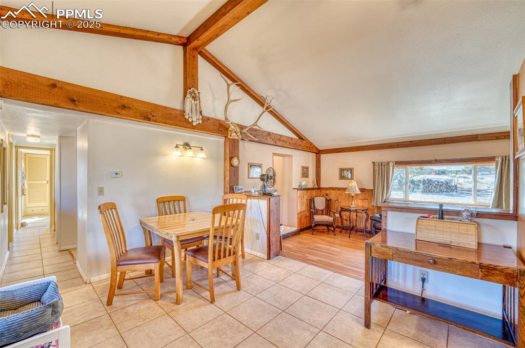 Image 13 of 45: Dining room featuring light tile patterned floors, beam ceiling, and high v