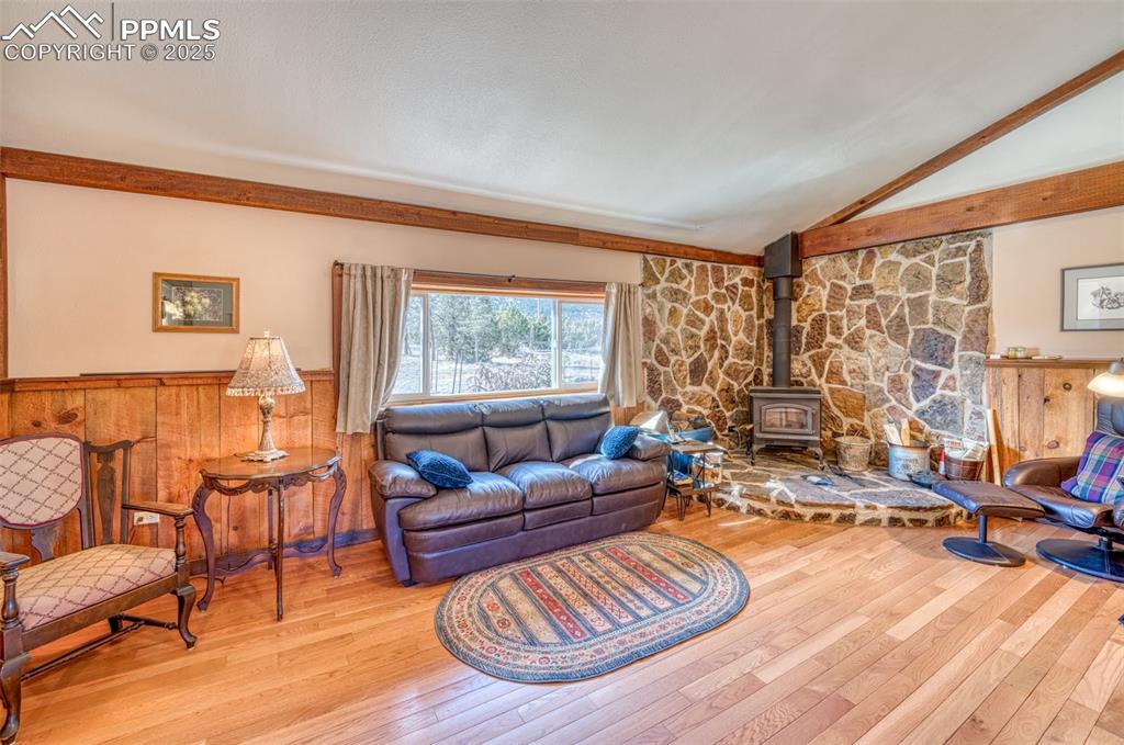 Image 15 of 45: Living room featuring a wood stove, hardwood / wood-style floors, vaulted c