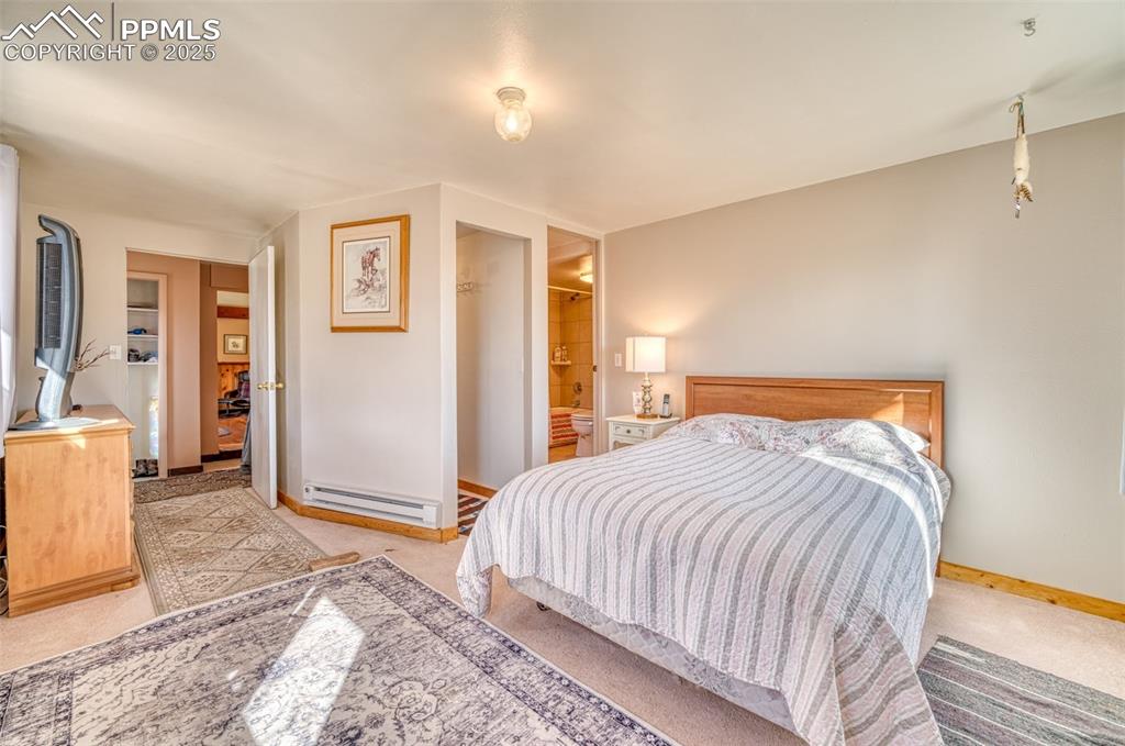 Image 18 of 45: Carpeted bedroom featuring a baseboard heating unit and baseboards