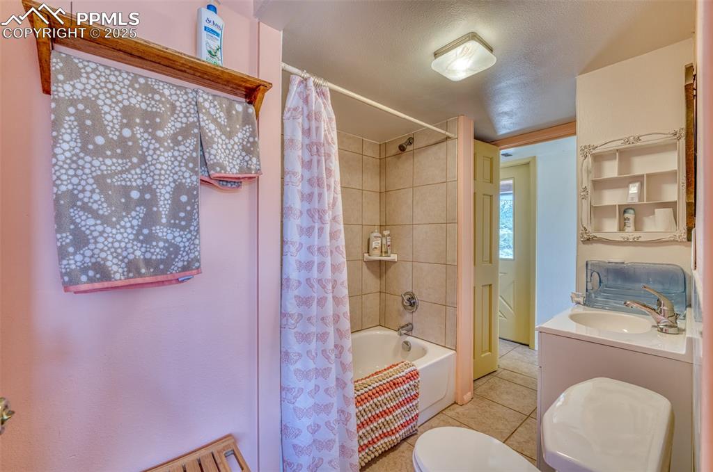 Image 25 of 45: Bathroom with tile patterned floors, shower / bathtub combination with curt