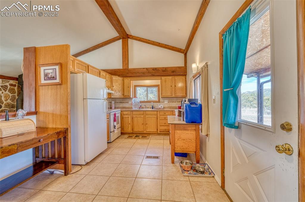 Image 7 of 45: Kitchen featuring white appliances, light countertops, light tile patterned
