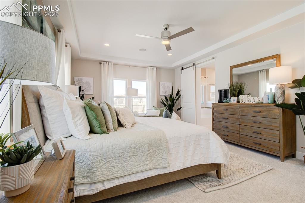 Image 16 of 27: Bedroom with a barn door, light carpet, connected bathroom, recessed lighti