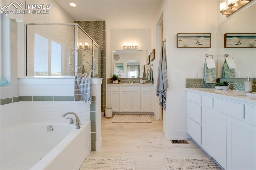 Image 18 of 27: Full bath featuring wood finished floors, a bath, vanity, a walk in shower,
