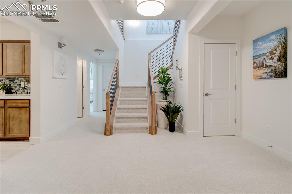 Image 26 of 27: Carpeted foyer featuring stairway and baseboards