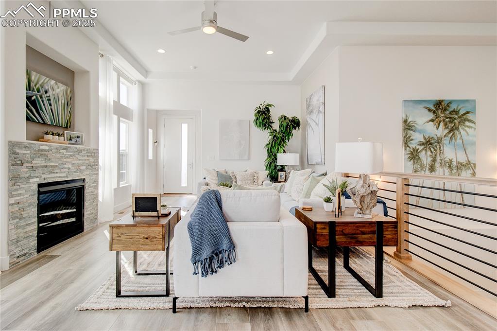 Image 4 of 27: Living area with a ceiling fan, wood finished floors, and a fireplace