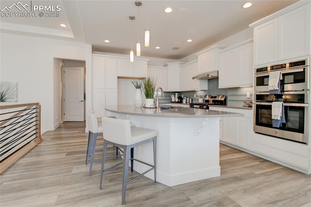 Image 9 of 27: Kitchen with double oven, a kitchen breakfast bar, recessed lighting, stove