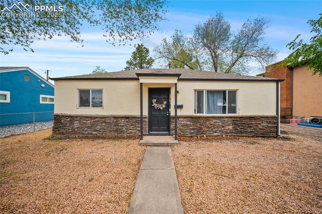 Caption: View of front of home featuring stone siding, stucco siding, and fence
