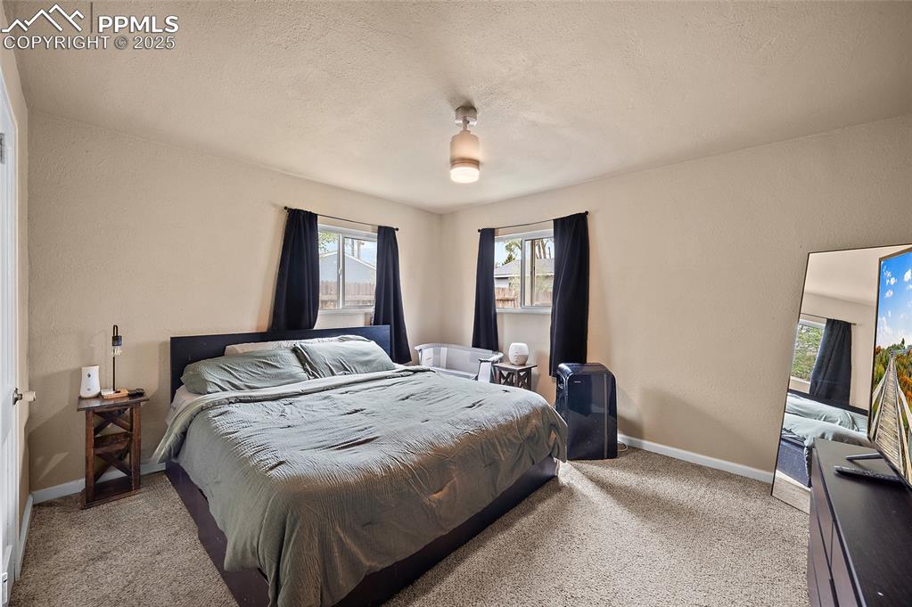 Image 8 of 12: Bedroom with multiple windows, carpet floors, baseboards, and a textured ce