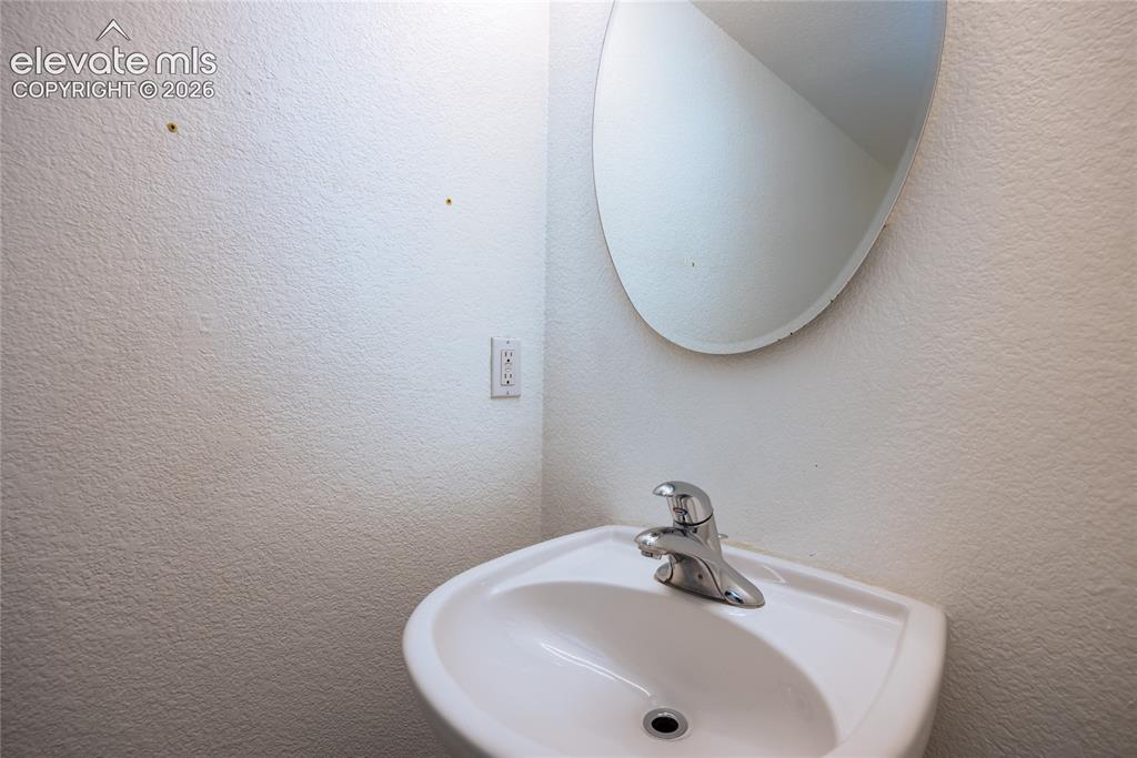 Image 12 of 31: Pedestal sink with a chrome faucet and a wall-mounted oval mirror