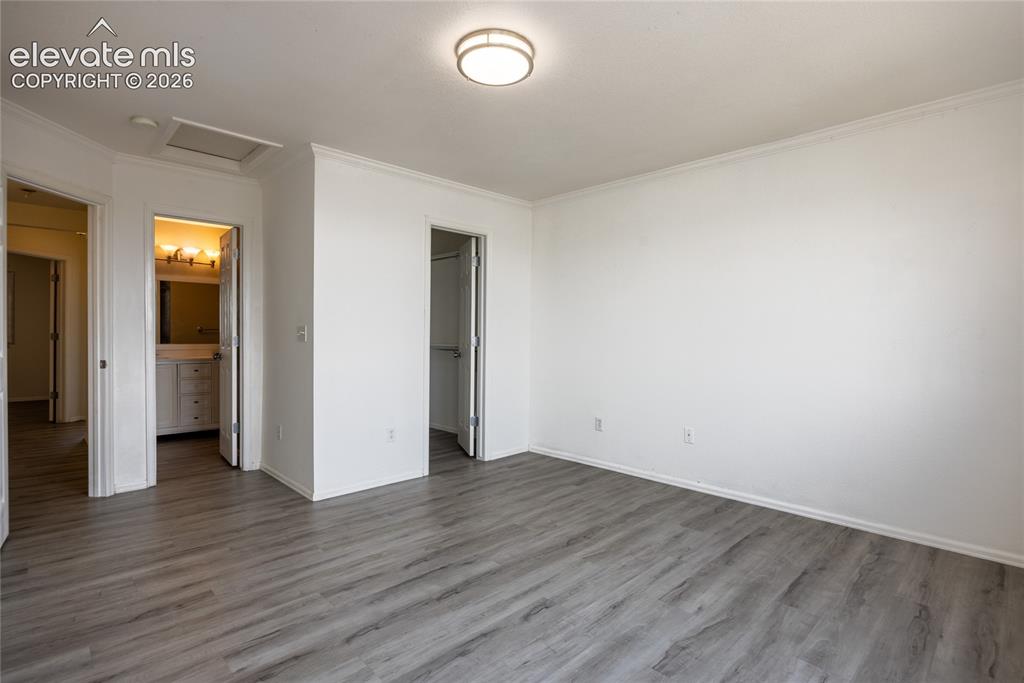 Image 14 of 31: Spacious room with wood-finish flooring, crown molding, and a flush mount c