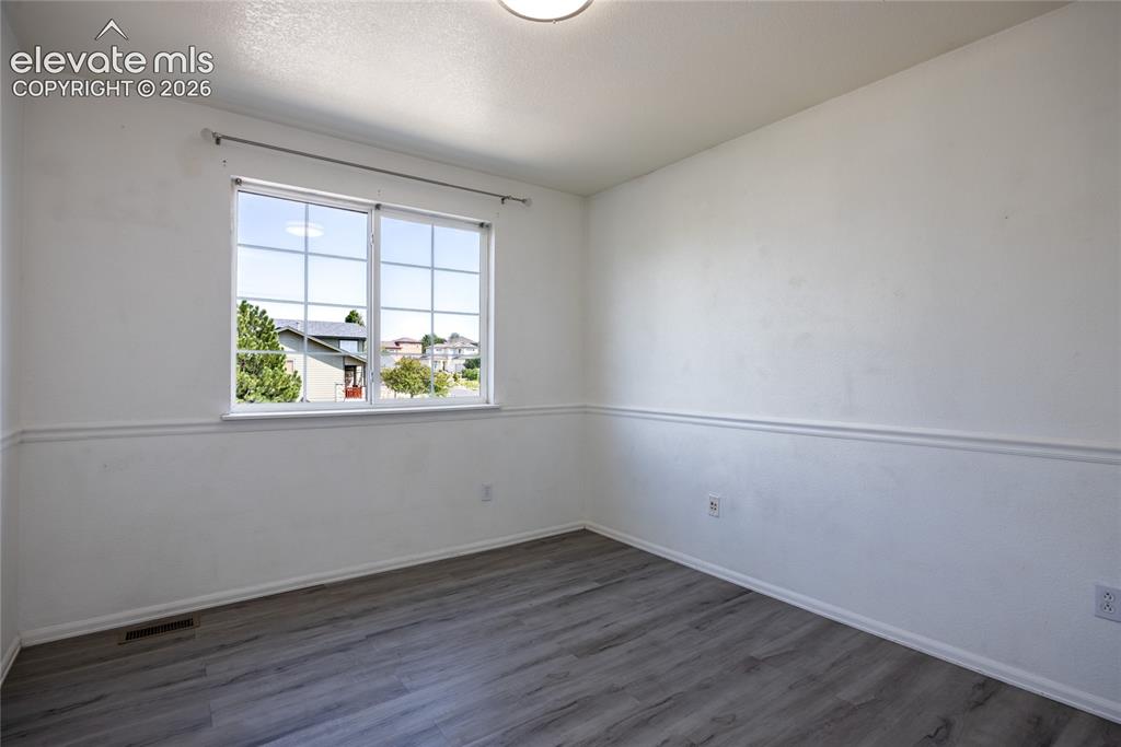 Image 17 of 31: White walls with decorative chair rail, wood-finish flooring, and a multi-p