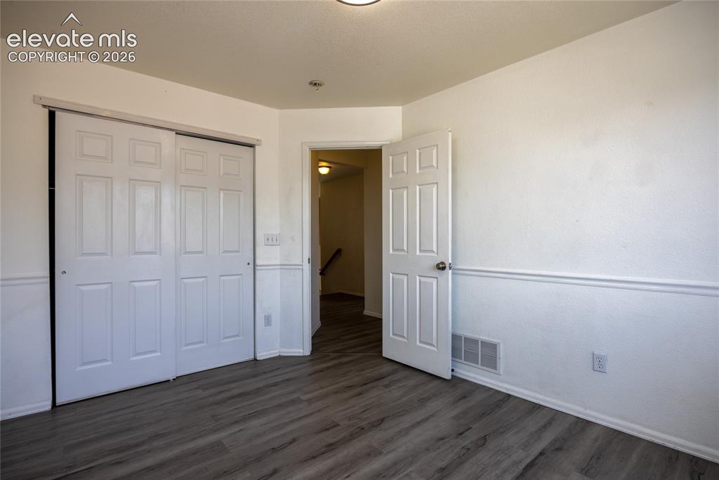 Image 18 of 31: Wood-finish flooring, white paneled doors, white walls, and wainscoting