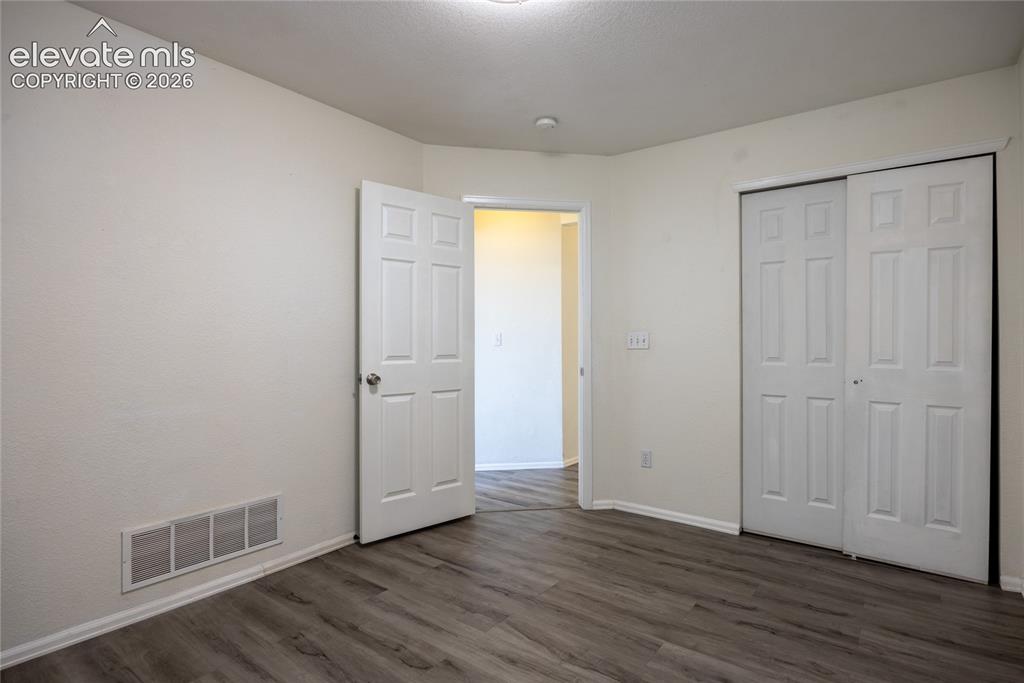 Image 20 of 31: Wood-finish flooring with white baseboards, a white paneled door, and white