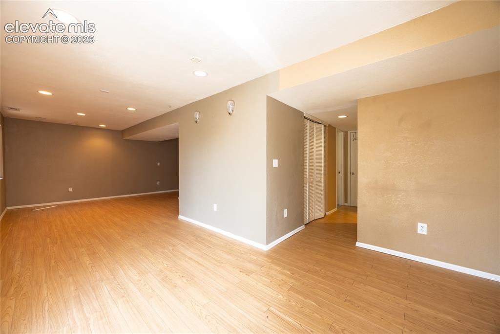Image 23 of 31: Expansive living area with wood-finish flooring, recessed lighting, and neu
