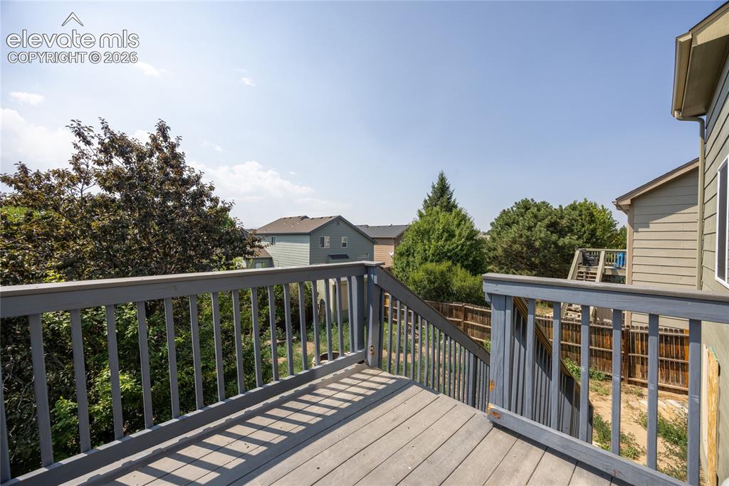 Image 26 of 31: Elevated wood deck with baluster railing, offering exterior access and surr