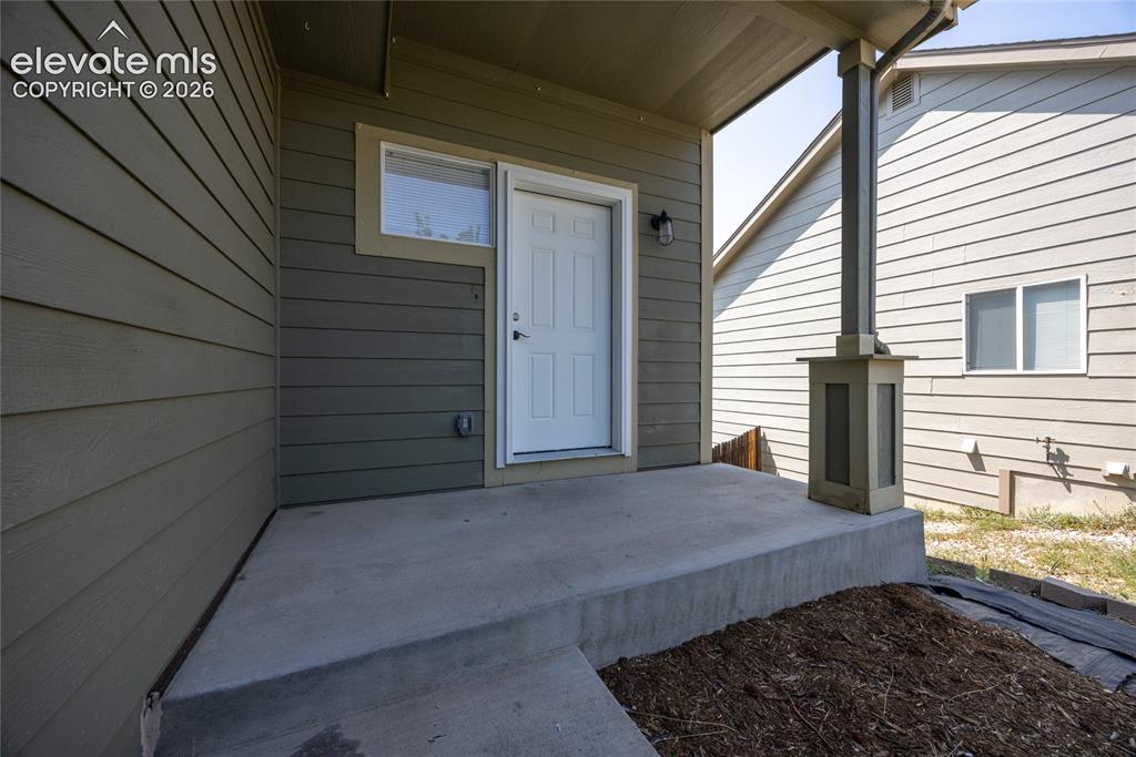 Image 5 of 31: Covered entry with concrete patio, siding exterior, exterior lighting fixtu