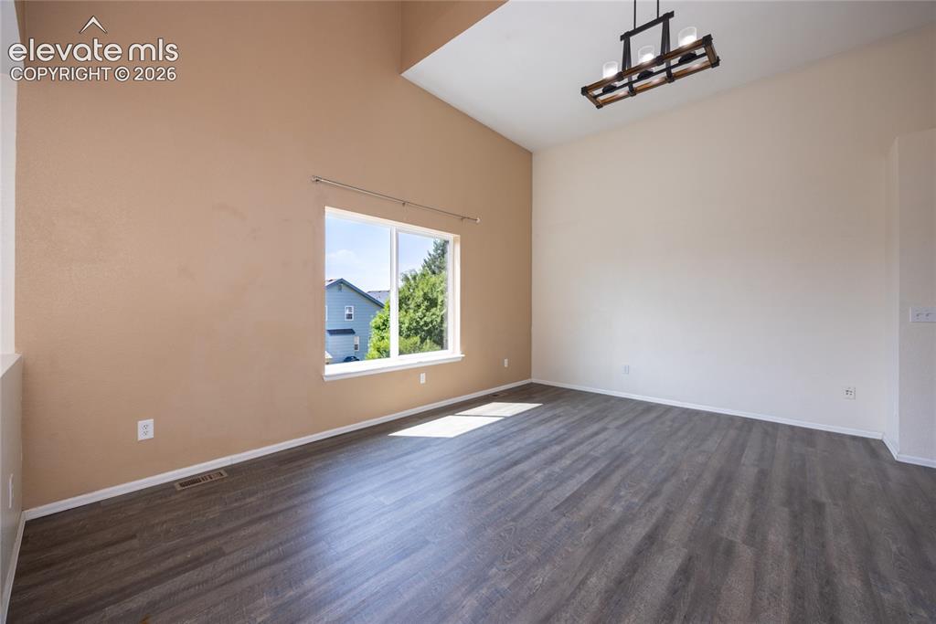 Image 6 of 31: Vaulted ceilings with a decorative chandelier, wood-finish flooring, and a