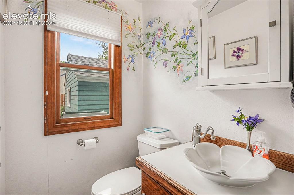 Image 12 of 27: Bathroom featuring a white floral vessel sink, wood-finish vanity, and a me
