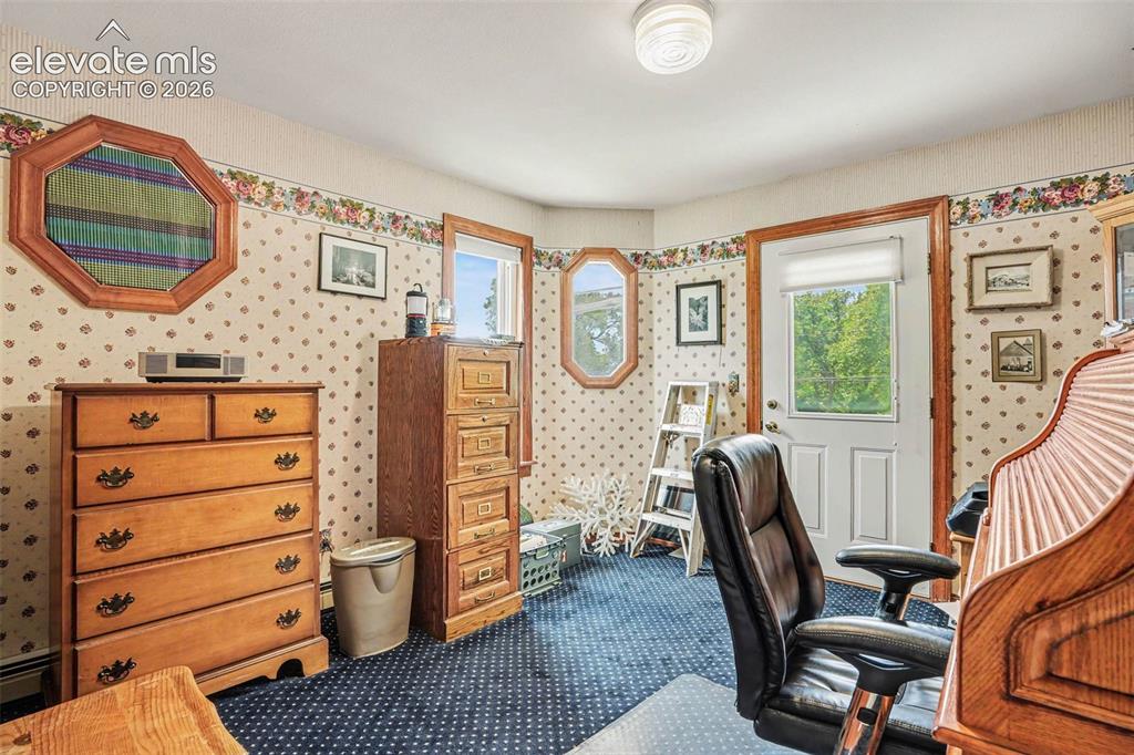 Image 13 of 27: Room featuring patterned wallpaper, crown molding, a white door with a wind