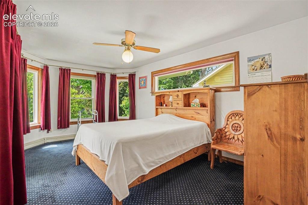Image 14 of 27: Carpeted room with a bay window featuring multiple windows, a ceiling fan w