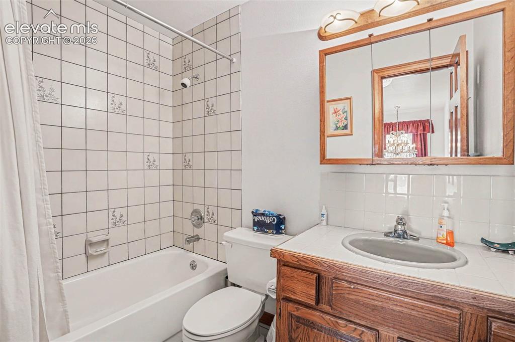 Image 15 of 27: Bathroom featuring a white subway tile surround, a built-in bathtub, a toil