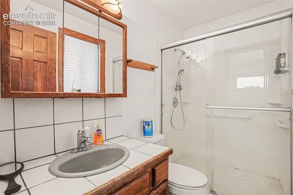 Image 16 of 27: Bathroom featuring a vanity with a drop-in sink, wood-finish cabinetry, and