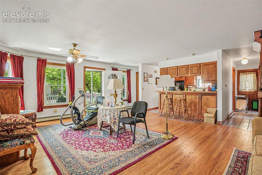 Image 7 of 27: Spacious living area featuring gleaming wood flooring, a ceiling fan, and m