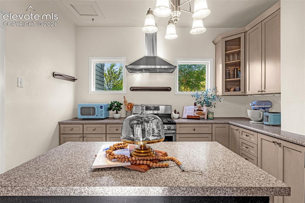 Image 10 of 33: Kitchen featuring an island with a speckled countertop, perimeter cabinetry