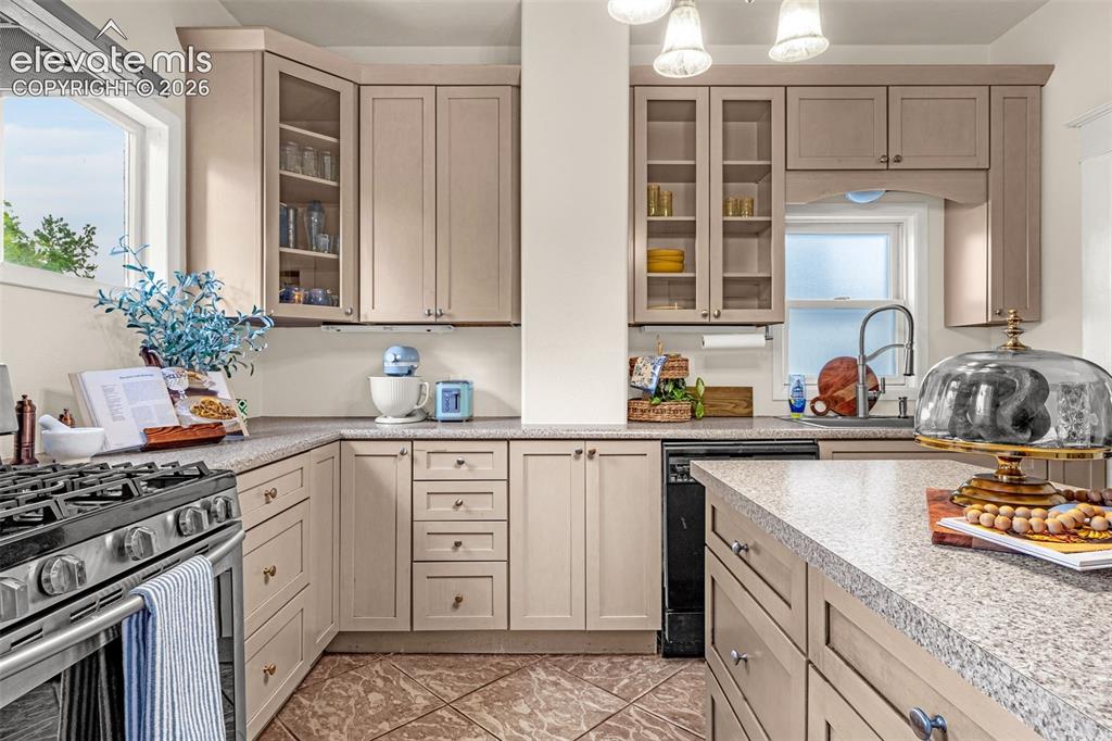 Image 13 of 33: U-shaped kitchen featuring light-toned cabinetry, speckled countertops, sta