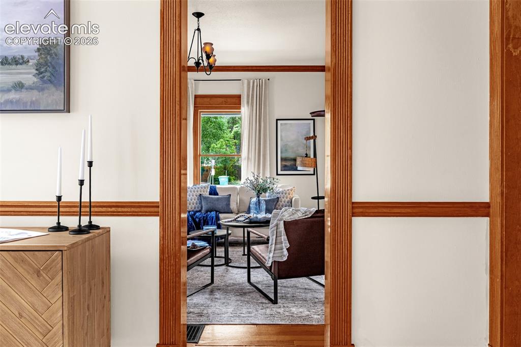 Image 15 of 33: View from dining area to living room, detailed woodwork, hardwoods, large w