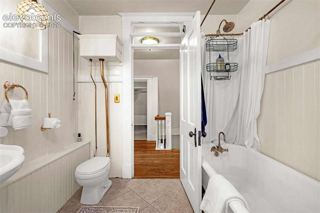Image 17 of 33: Bathroom with wainscoting, a high-tank toilet, a clawfoot tub, and a decora