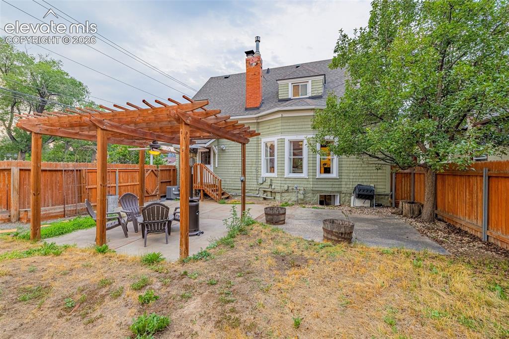 Image 27 of 33: Expansive patio featuring a wooden pergola with a ceiling fan, concrete har