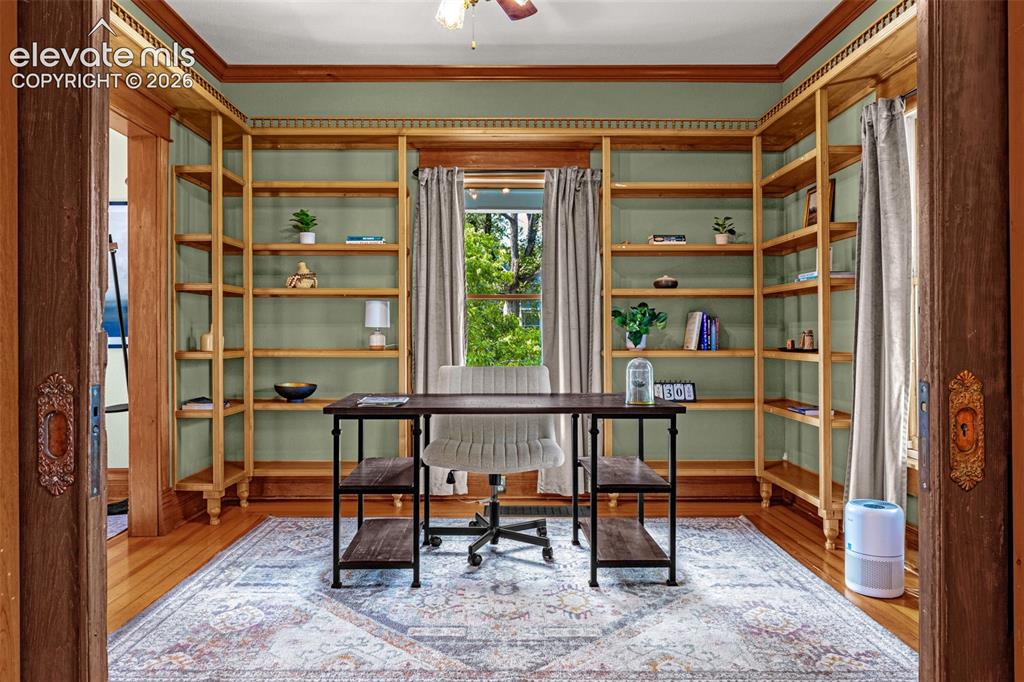 Image 4 of 33: Office w/ built-in shelving, wood-finish flooring, window with natural ligh