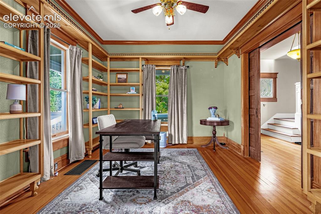 Image 5 of 33: Office w/ built-in shelving, wood-finish flooring, ceiling fan, and detaile