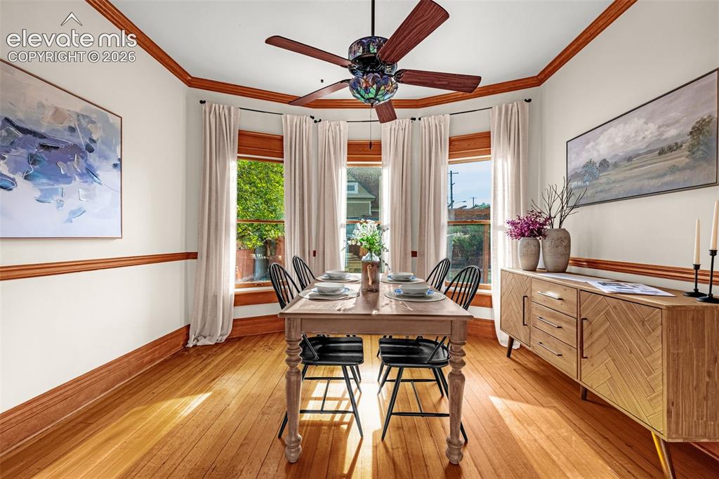 Image 8 of 33: Hardwood flooring, bay window with wood trim, ceiling fan, crown molding, a