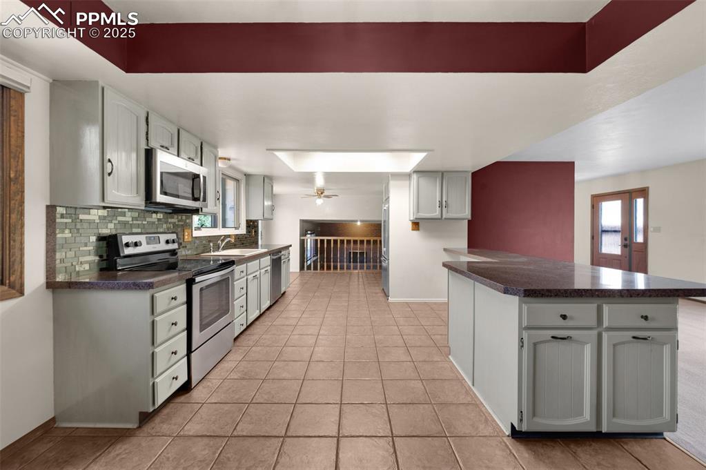 Image 19 of 47: Kitchen with stainless steel appliances, dark countertops, decorative backs
