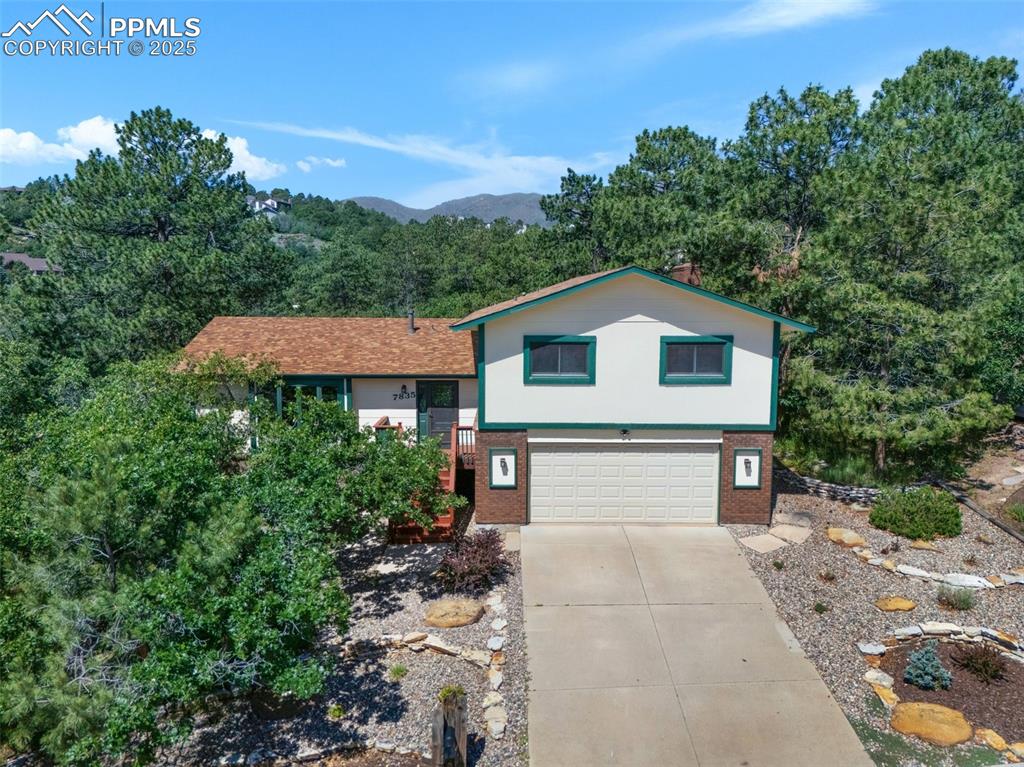 Image 2 of 47: Tri-level home with a garage, concrete driveway, and a mountain view