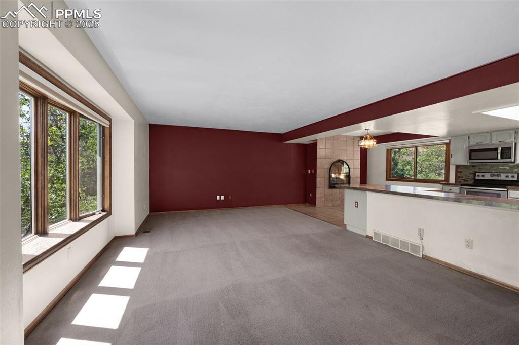 Image 9 of 47: Unfurnished living room with a chandelier and light carpet