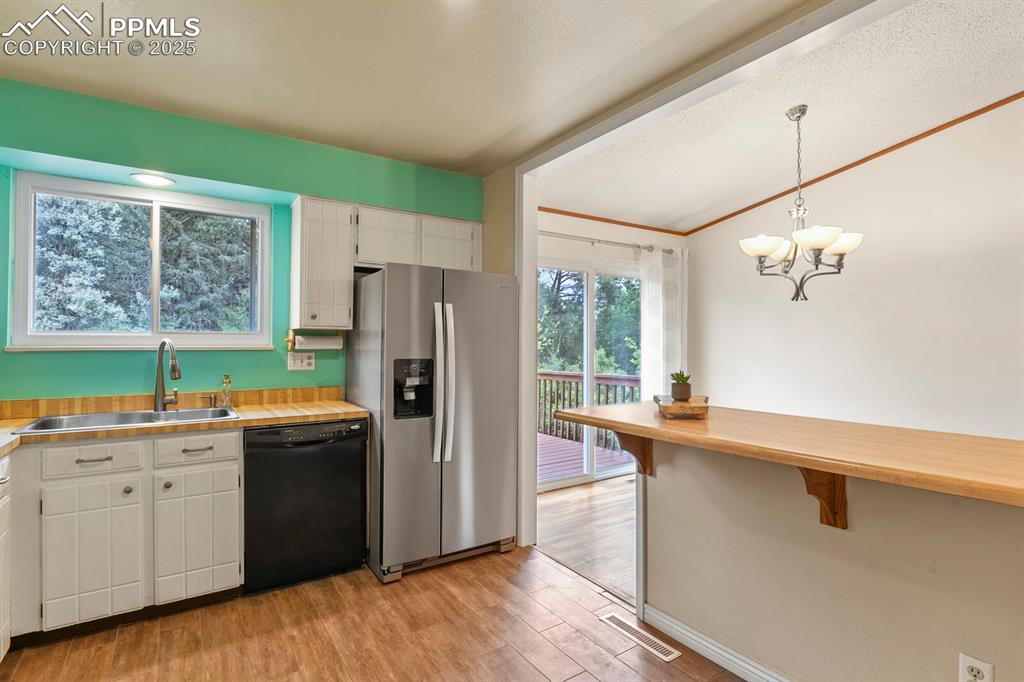 Image 13 of 39: Kitchen featuring stainless steel fridge, black dishwasher, light wood-styl