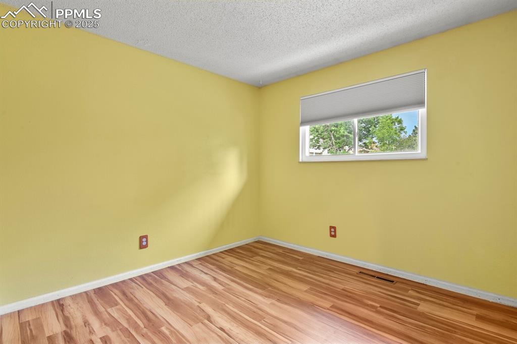Image 18 of 39: Second bedroom with light wood-type flooring and a textured ceiling