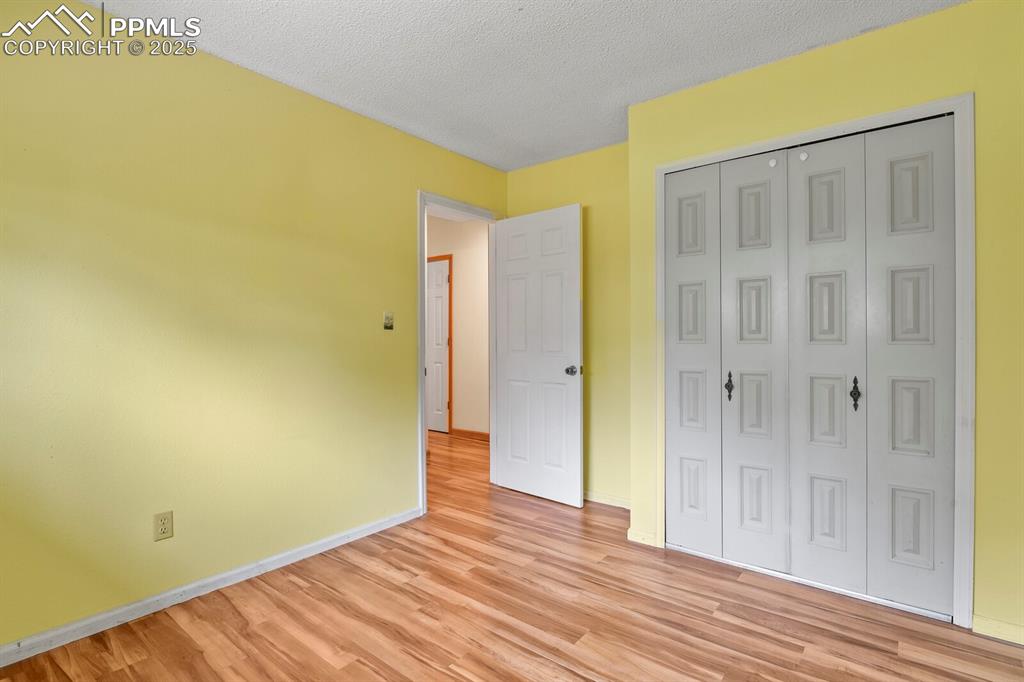 Image 19 of 39: Second bedroom featuring light wood-style floors, a closet, and a textured