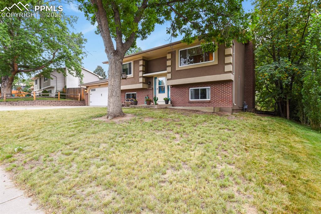 Image 2 of 39: Split foyer home featuring brick siding, a garage, a front lawn, and stucco