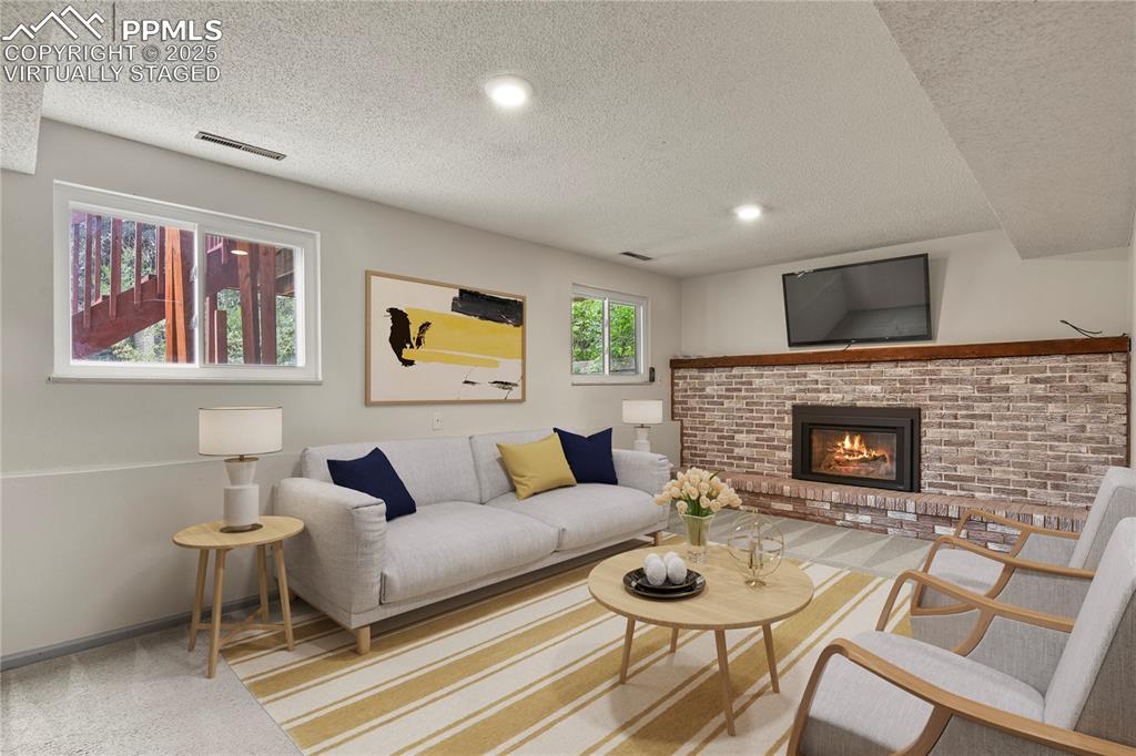 Image 21 of 39: Virtually Staged Family room featuring carpet, a textured ceiling, and a fi